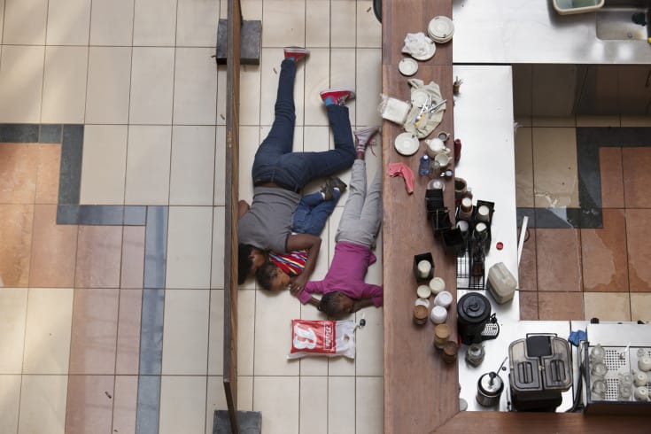 A woman and children hide inside Westgate Mall in Nairobi, Kenya, Sept. 21, 2013. A group of armed men attacked the upscale shopping mall in Nairobi on Saturday, killing at least 59 people and wounding at least 175. On Sunday, extremists holding an unknown number of hostages continued a siege after Kenyan security forces surrounded the facility. (Tyler Hicks/The New York Times)
