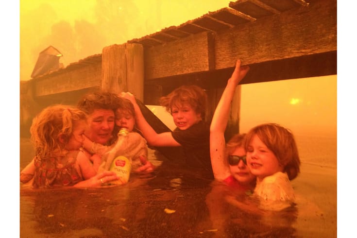 In this Jan. 4, 2013, photo provided by the Holmes family, Tammy Holmes, second from left, and her grandchildren, two-year-old Charlotte Walker, left, four-year-old Esther Walker, third from left, nine-year-old Liam Walker, eleven-year-old Matilda, second from right, and six-year-old Caleb Walker, right, take refuge under a jetty as a wildfire rages near-by  in the Tasmanian town of Dunalley, east of the state capital of Hobart, Australia. The family credits God with their survival from the fire that destroyed around 90 homes in Dunalley. Record temperatures across southern Australia cooled Wednesday, Jan. 9, 2013, reducing the danger from scores of raging wildfires but likely bringing only a brief reprieve from the summer’s extreme heat and fire risk. (AP Photo/Holmes Family, Tim Holmes) EDITORIAL USE ONLY AUSTRALIA OUT