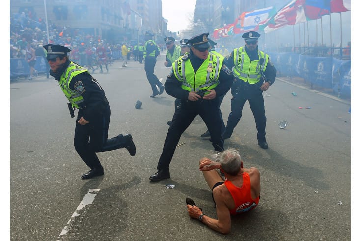 BOSTON - APRIL 15: Police officers with their guns drawn hear the second explosion down the street. The first explosion knocked down a runner at the finish line of the 117th Boston Marathon. (Photo by John Tlumacki/The Boston Globe via Getty Images)